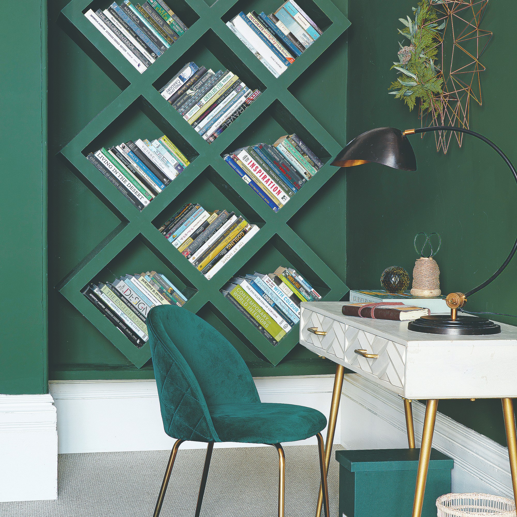 A home office painted in dark green with contrasting white skirting boards